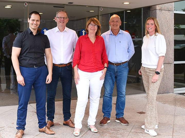 De vijf medewerkers van Schrauwers & Van der Neut staan samen voor de ingang van het kantoor in Badhoevedorp